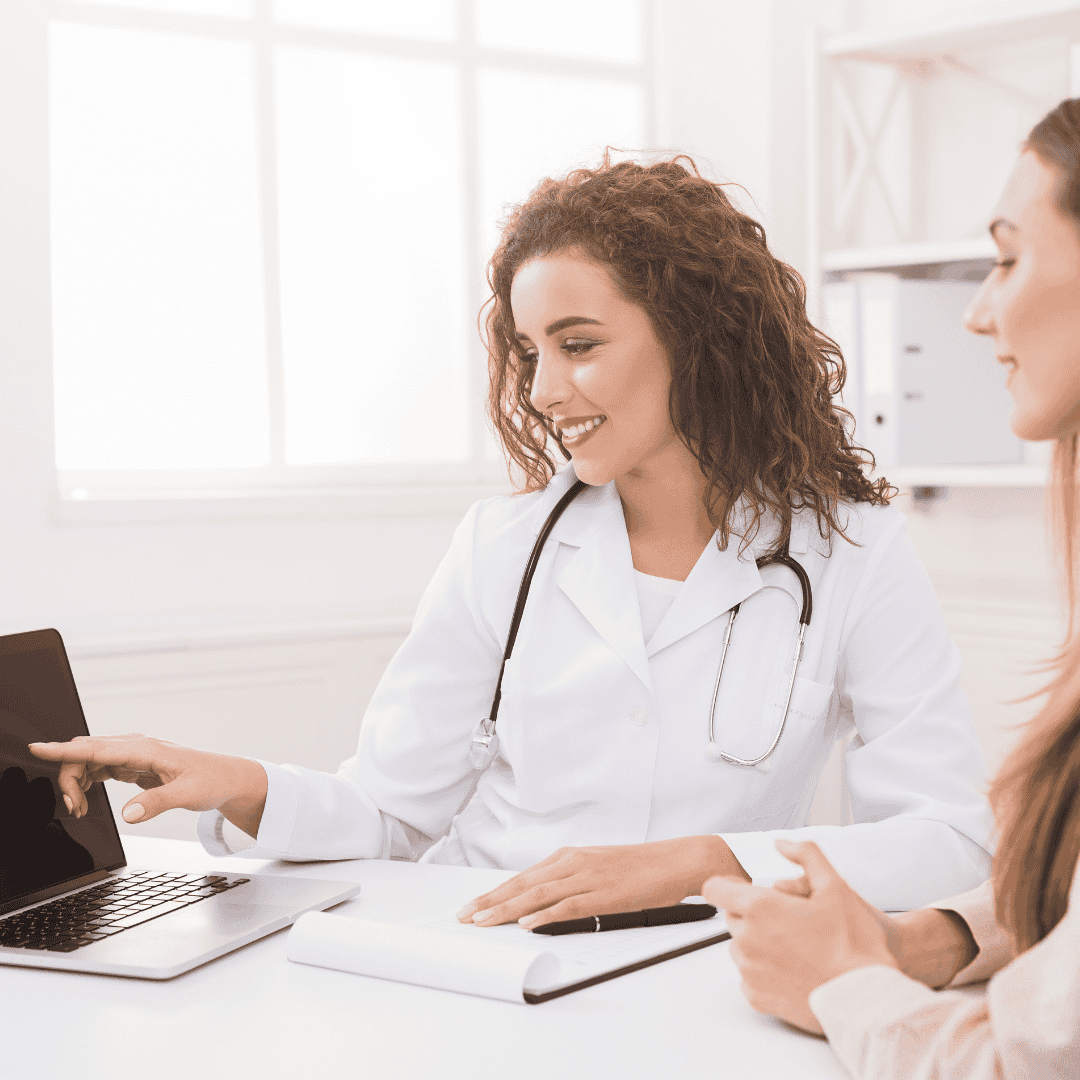 A healthcare provider sits with a patient, reviewing her health record charts on a tablet.